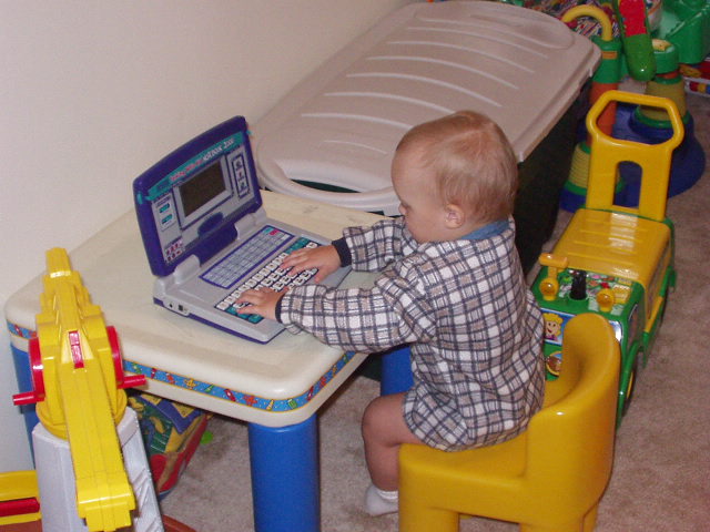Elijah is working on his big brothers computer just like Daddy