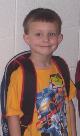 Timothy was standing up against the wall waiting to go into class.