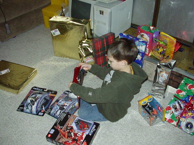 Timothy is busy opening all of his Christmas presents.