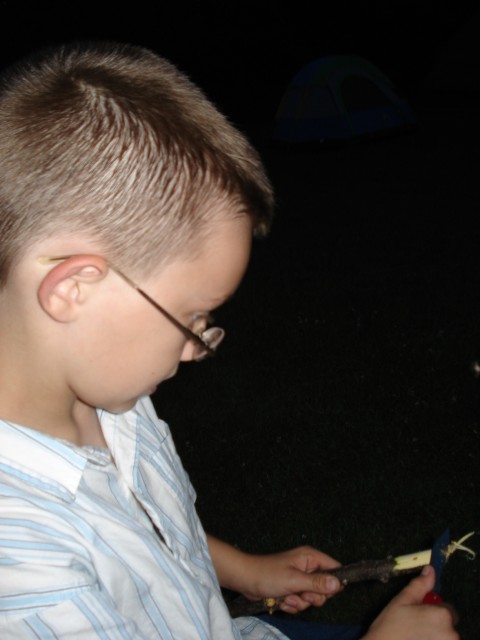 Timmy is whittling a tent stake.