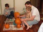 Elijah draws a face on his pumpkin.